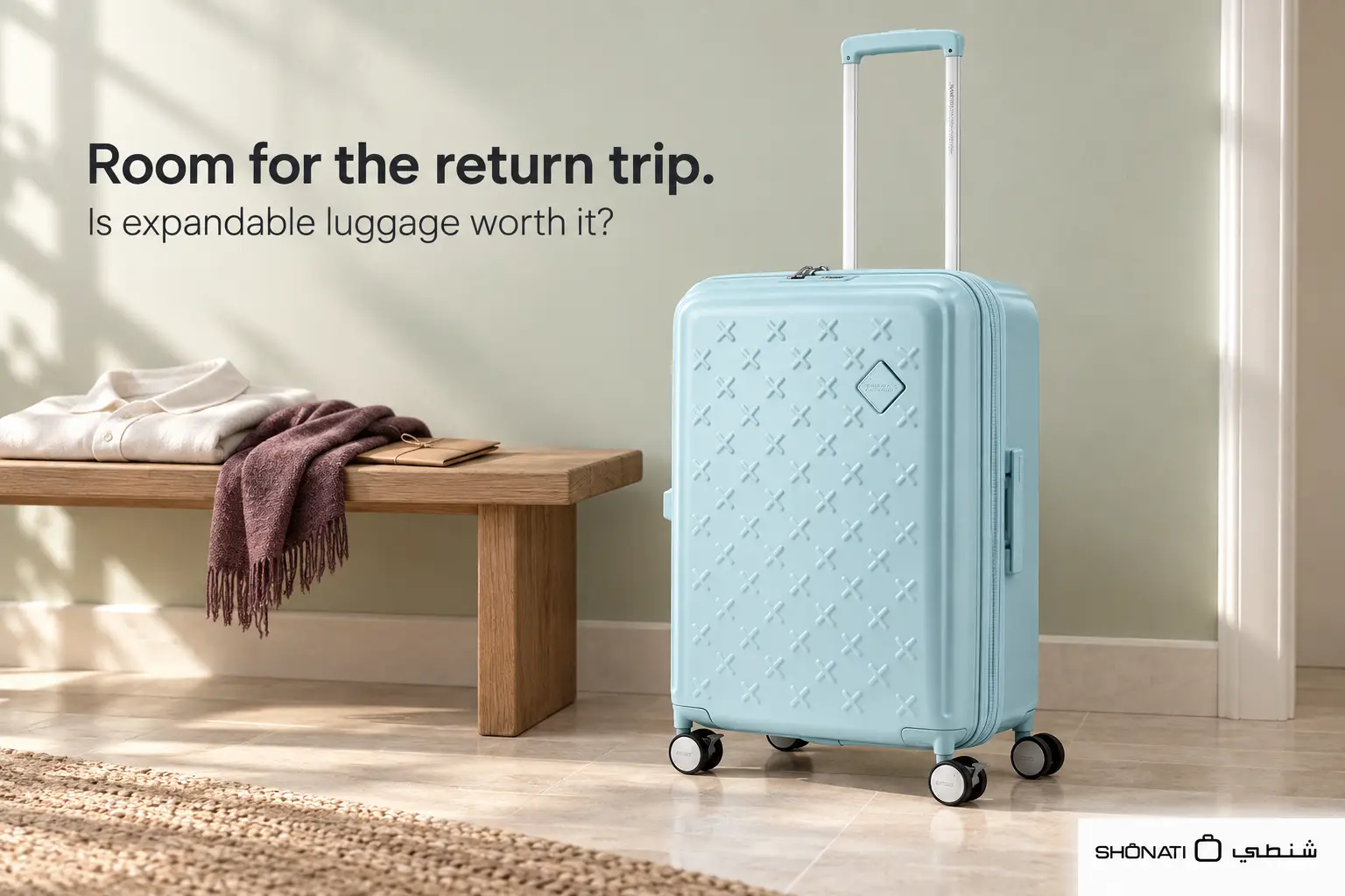 Light blue American Tourister Paxtra expandable suitcase beside a wooden bench with folded clothes.