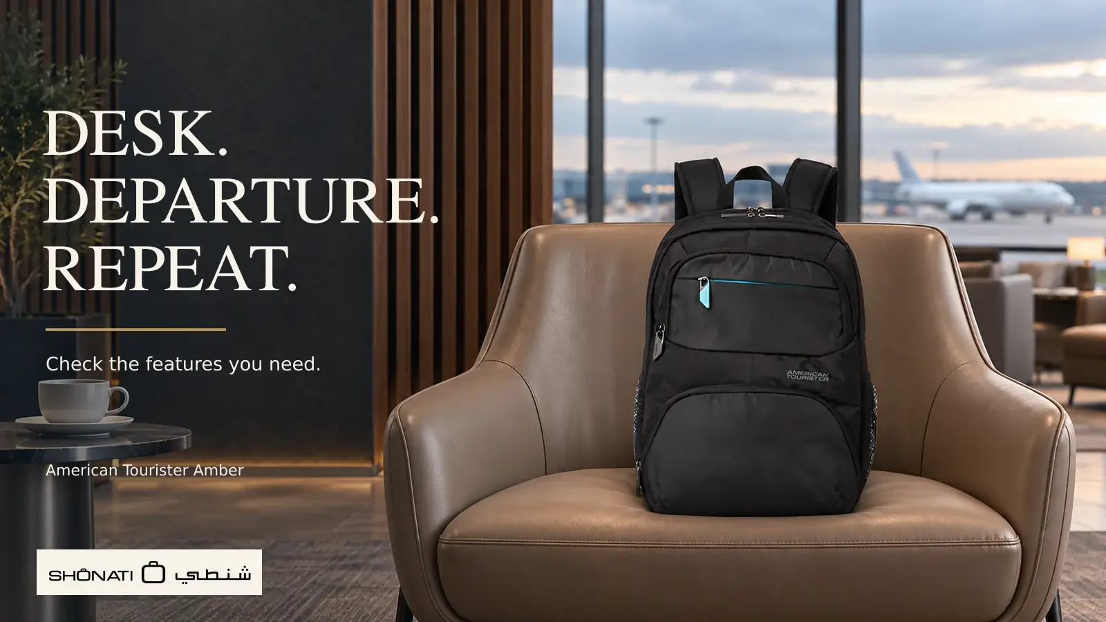 Black American Tourister Amber backpack with blue accents resting on a taupe airport lounge chair.