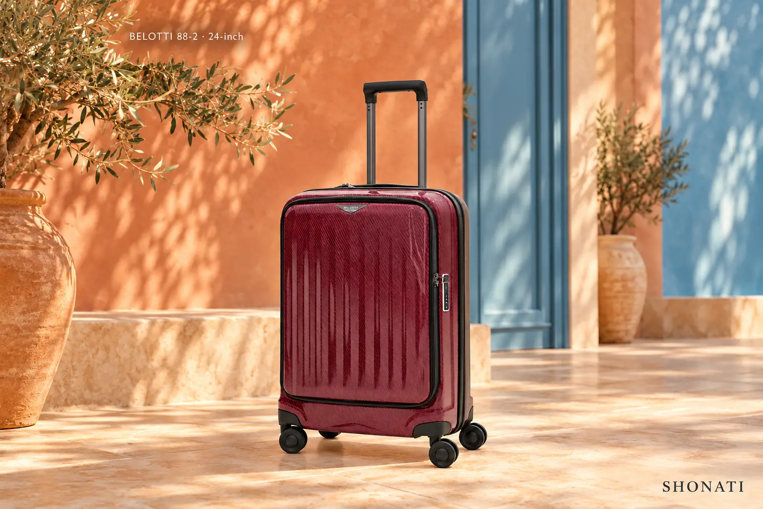 BELOTTI 88-2 · 24-inch Wine-red BELOTTI 88-2 suitcase in a sunlit terracotta and blue architectural setting