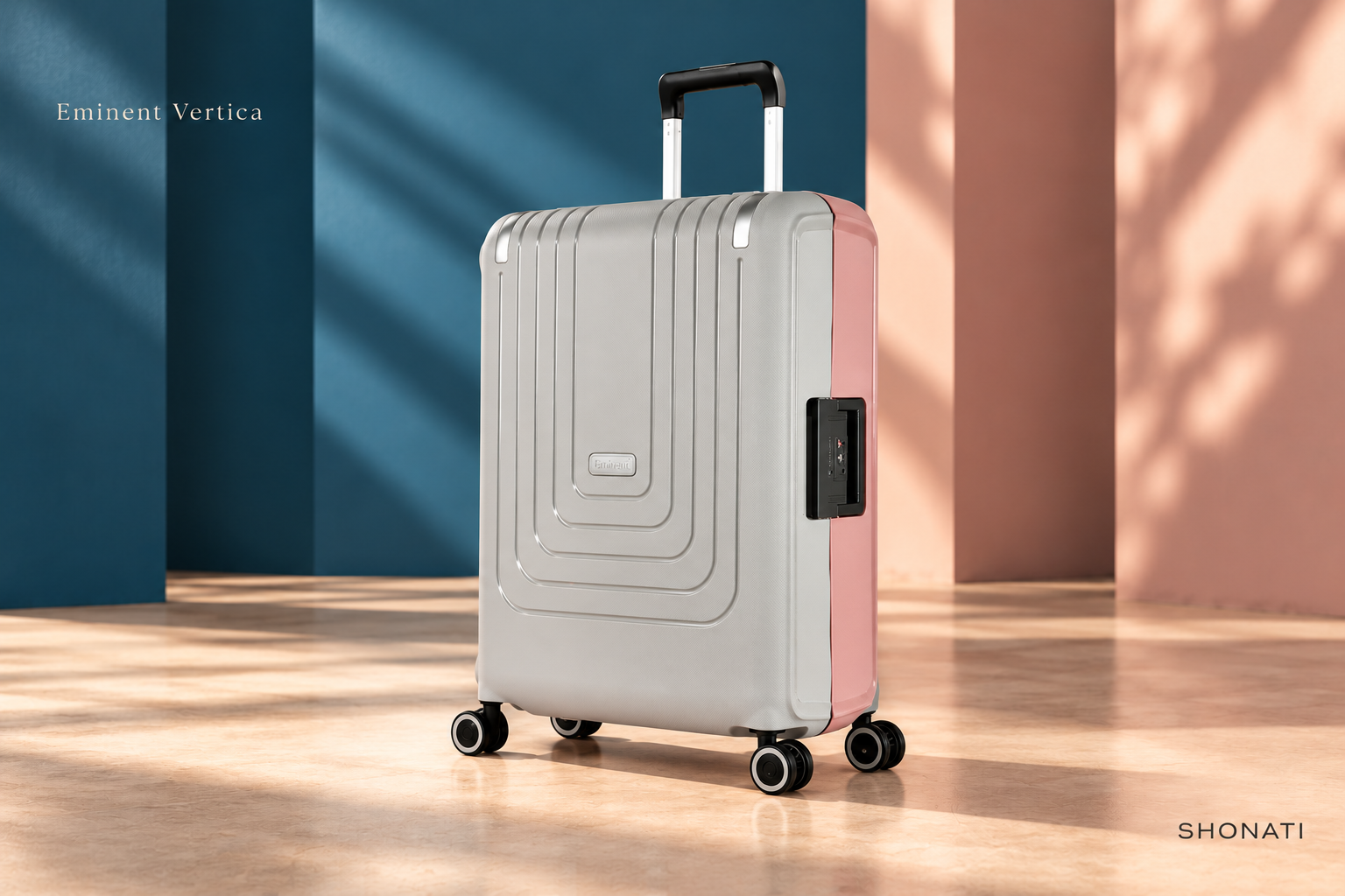 Eminent Vertica · Grey/Pink Front view of grey and pink Eminent Vertica suitcase against blue and blush architecture